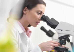 mulheres na ciência, mulher cientista olhando por um microscópio