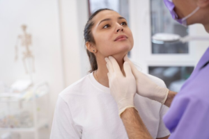 Um médico examina o pescoço de uma paciente durante uma consulta médica de rotina. Ele está verificando se há algum inchaço ou nódulos que possam indicar problemas de saúde.