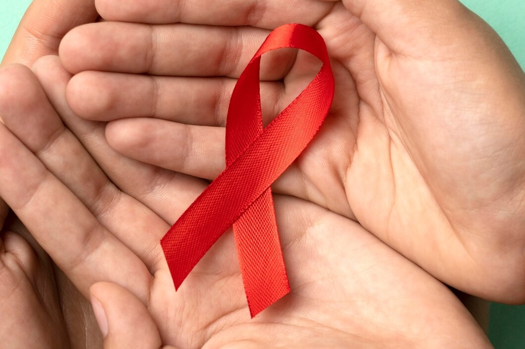 Mãos segurando um laço de fita vermelha, símbolo do combate à Leucemia.
