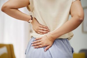 Mulher com dor nas costas representando os sintomas da fibromialgia, condição que agora é considerada deficiência por lei no Brasil.